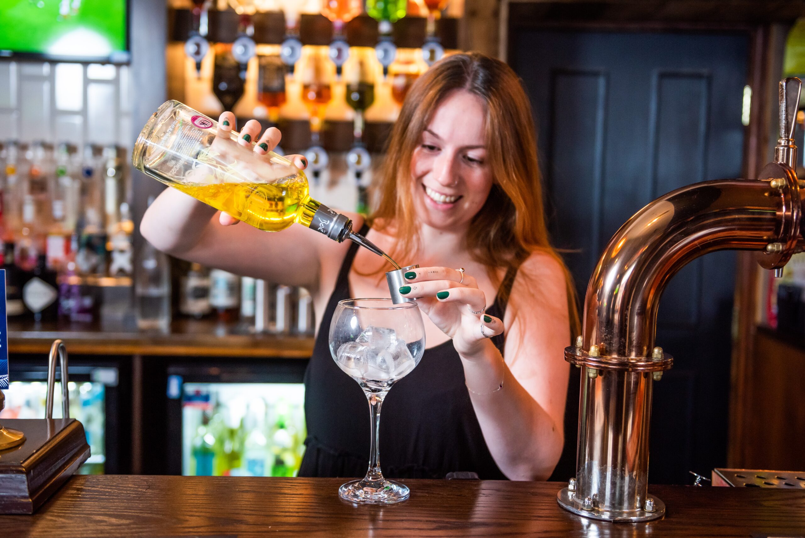 A woman pouring a drink at a bar.