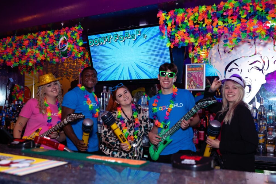 Popworld team members and managers wearing Popworld merchandise behind the bar.